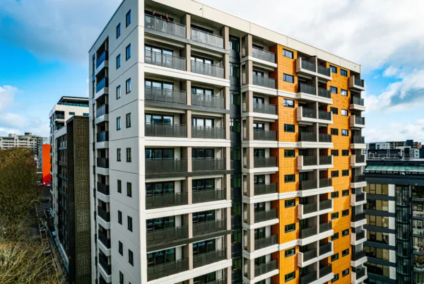 Exterior phoot of the Te Mātāwai apartment building. The multi-story building is grey with bright yellow accents along some windows.
