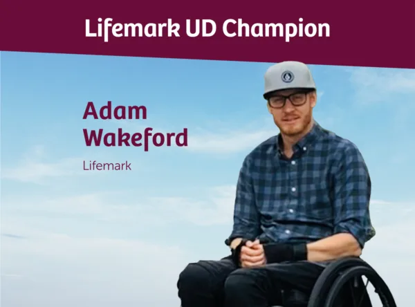 Photo of Lifemark assessor Adam Wakeford. He is wearing a baseball cap and a blue checked shirt, and is a wheelchair user.
