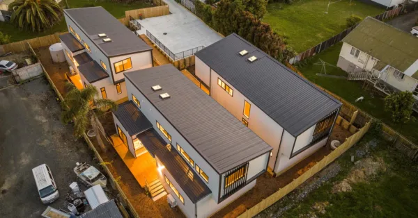 An overhead photo of the 3 Project Pacific houses, which are joined by a shared courtyard. It is evening and there is a welcoming glow from the windows.