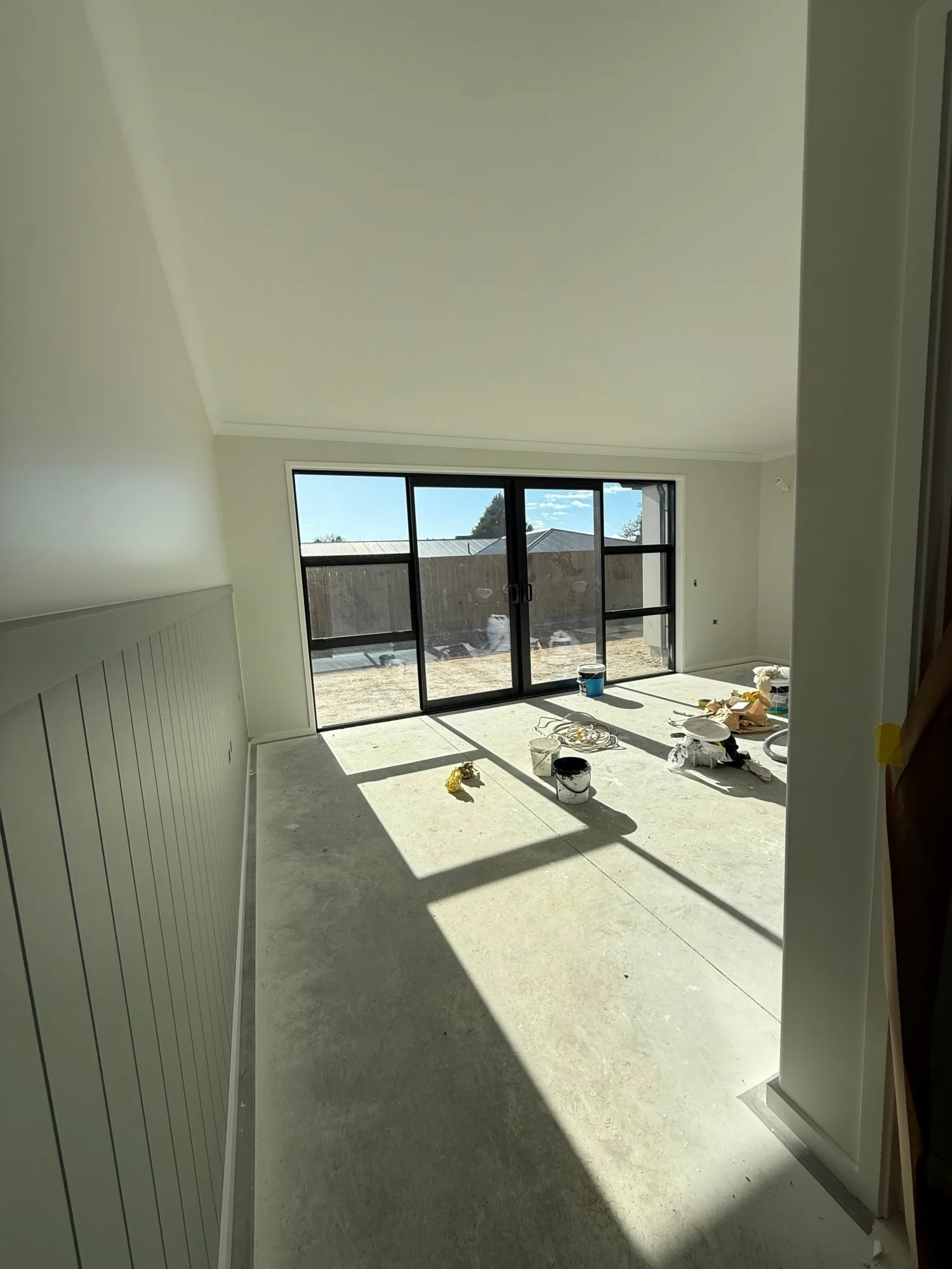 A view into one of the rooms in the units. The walls are painted a beige colour with half batten details, and there is no flooring yet.