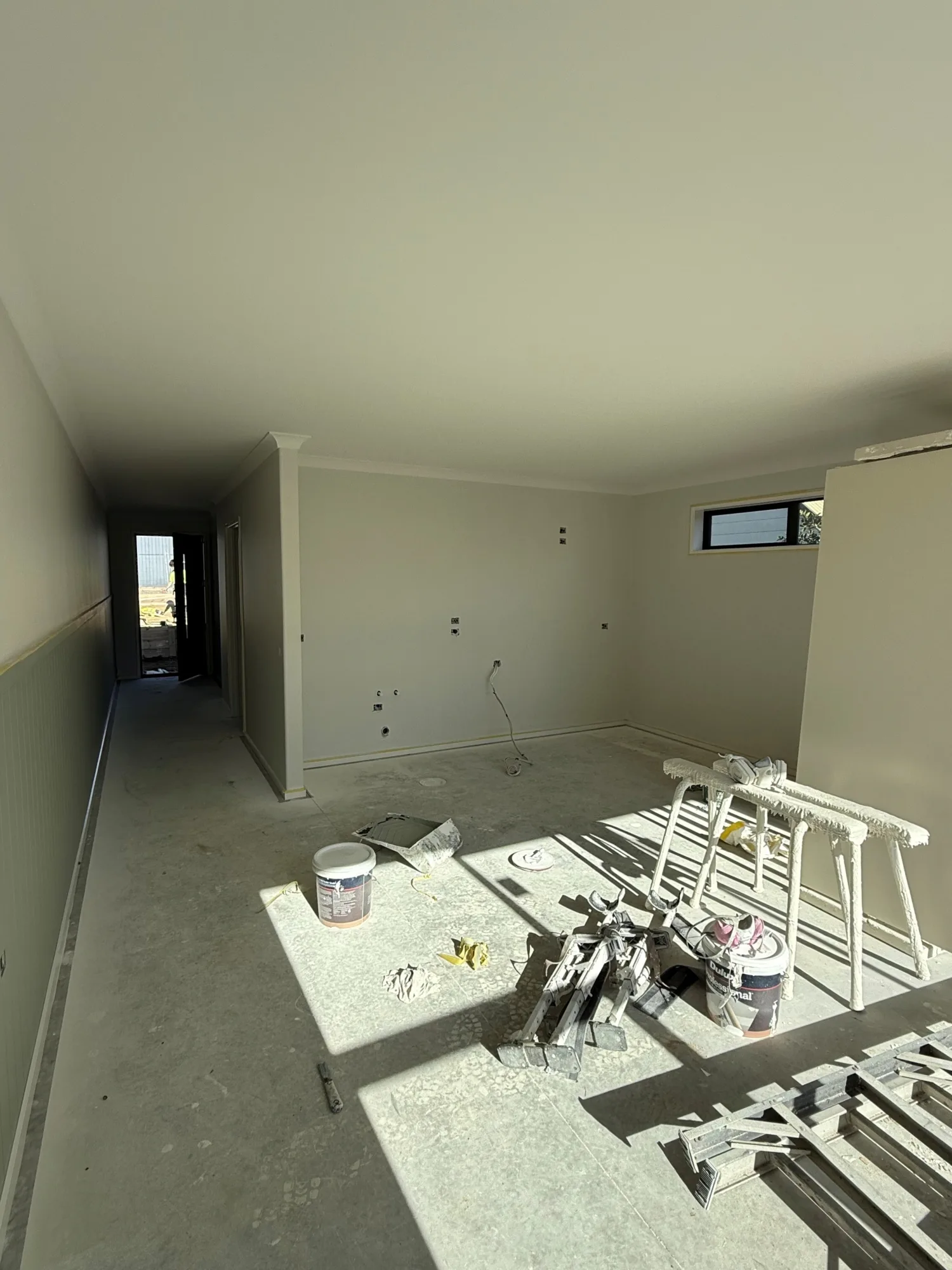 Another view into one of the rooms in the units. The walls are painted a beige colour with half batten details, and there is no flooring yet.