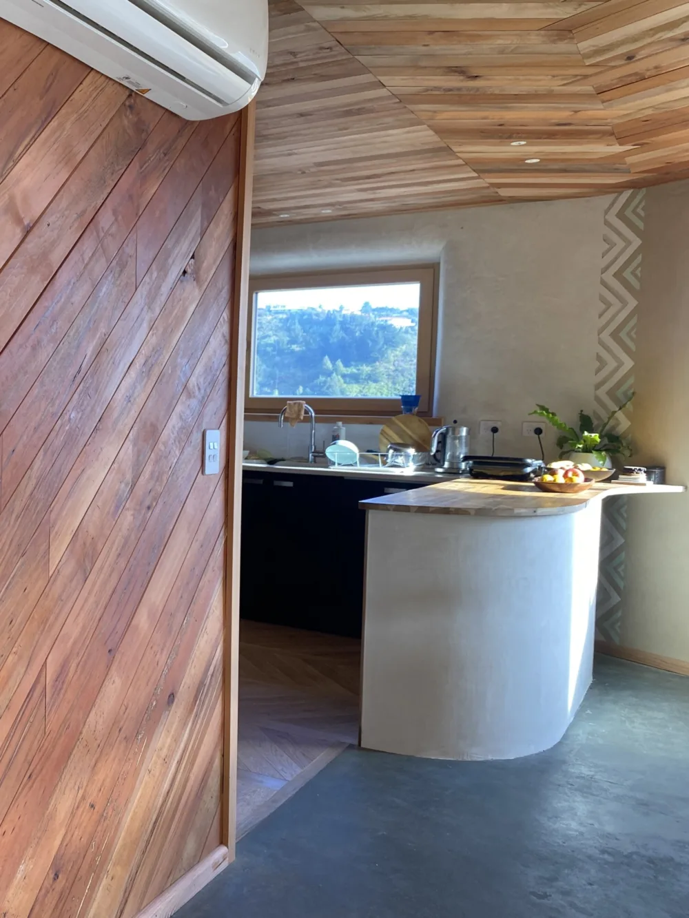 The kitchen, with its curved bench and rustic wood feature wall.