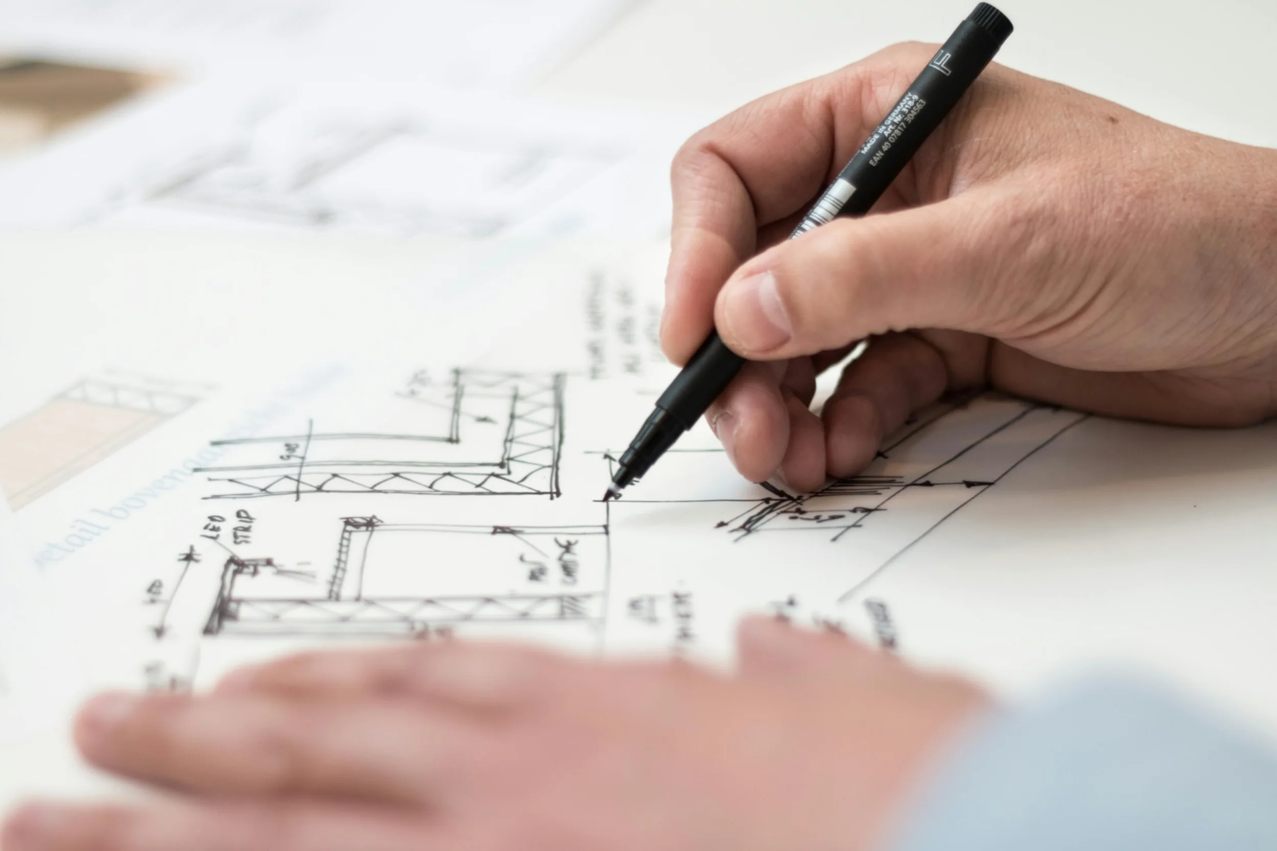Hands drawing on a set of blueprints.